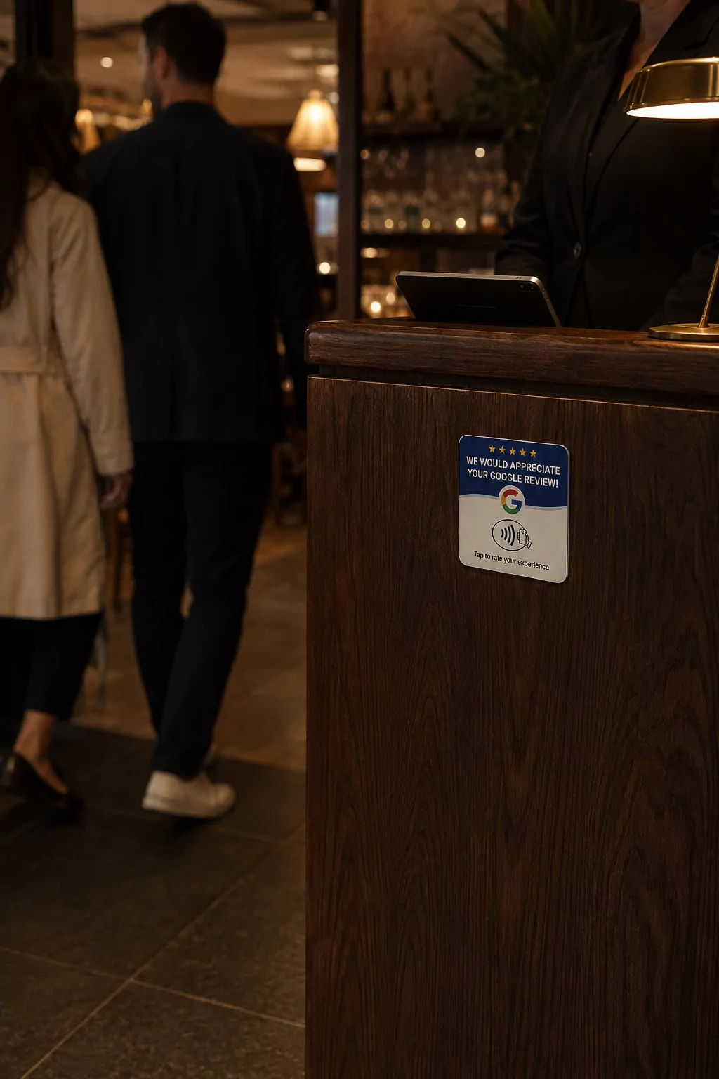 The blue and white review plate on the side of a dark wood restaurant host stand, with two diners walking past out of focus